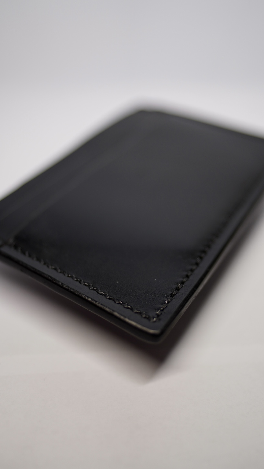 Detaliu al cusăturii și cantului card holderului negru
